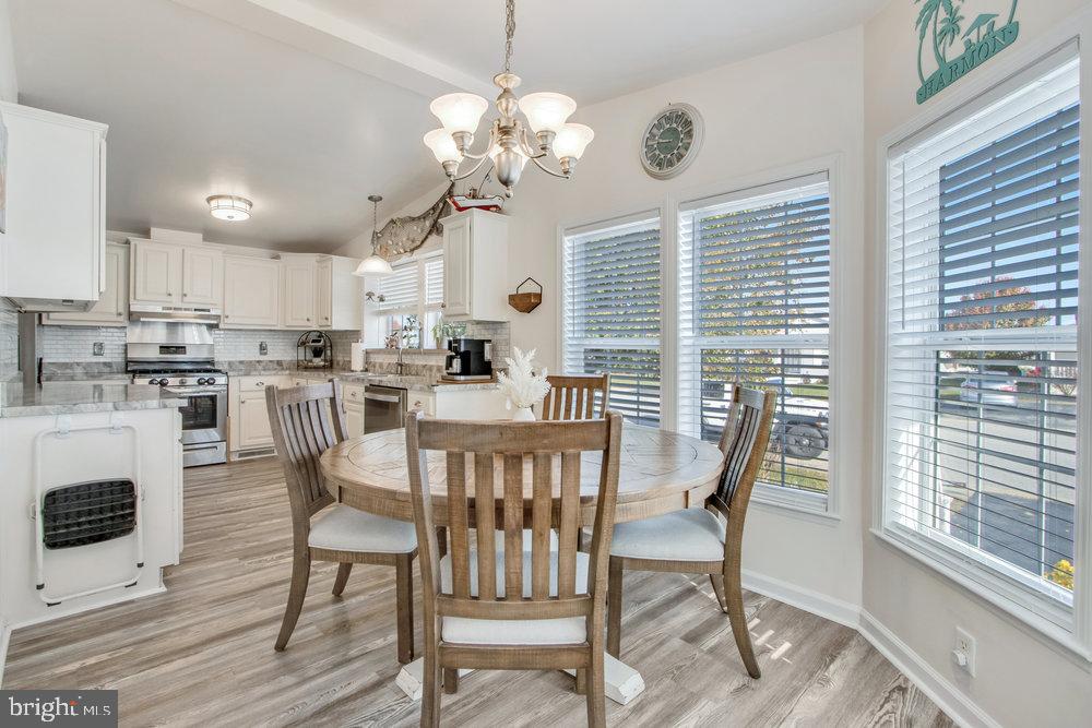 1125 Lorenzo Lane, Unit 274 Smyrna, DE 19977 - Photo 8 of 43 a view of a dining room with furniture a chandelier and wooden floor