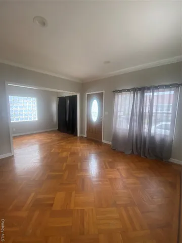 a view of an empty room with window and wooden floor