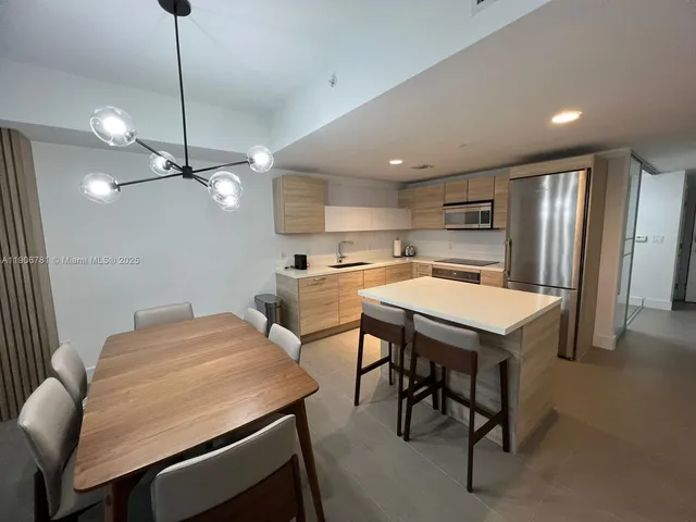 a kitchen with stainless steel appliances a table chairs and white cabinets