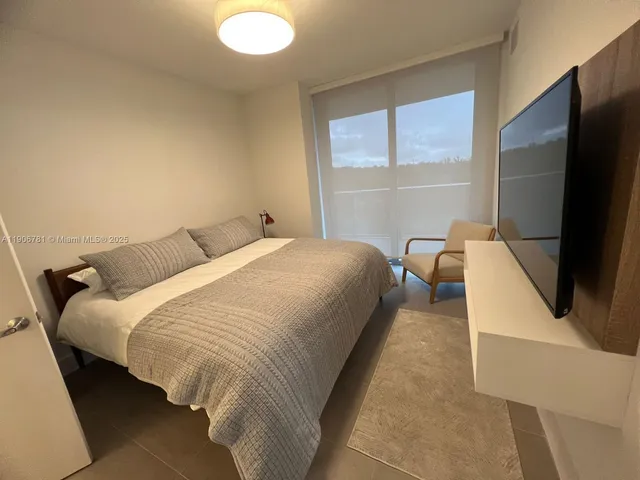 a bed room with a bed tv and a window