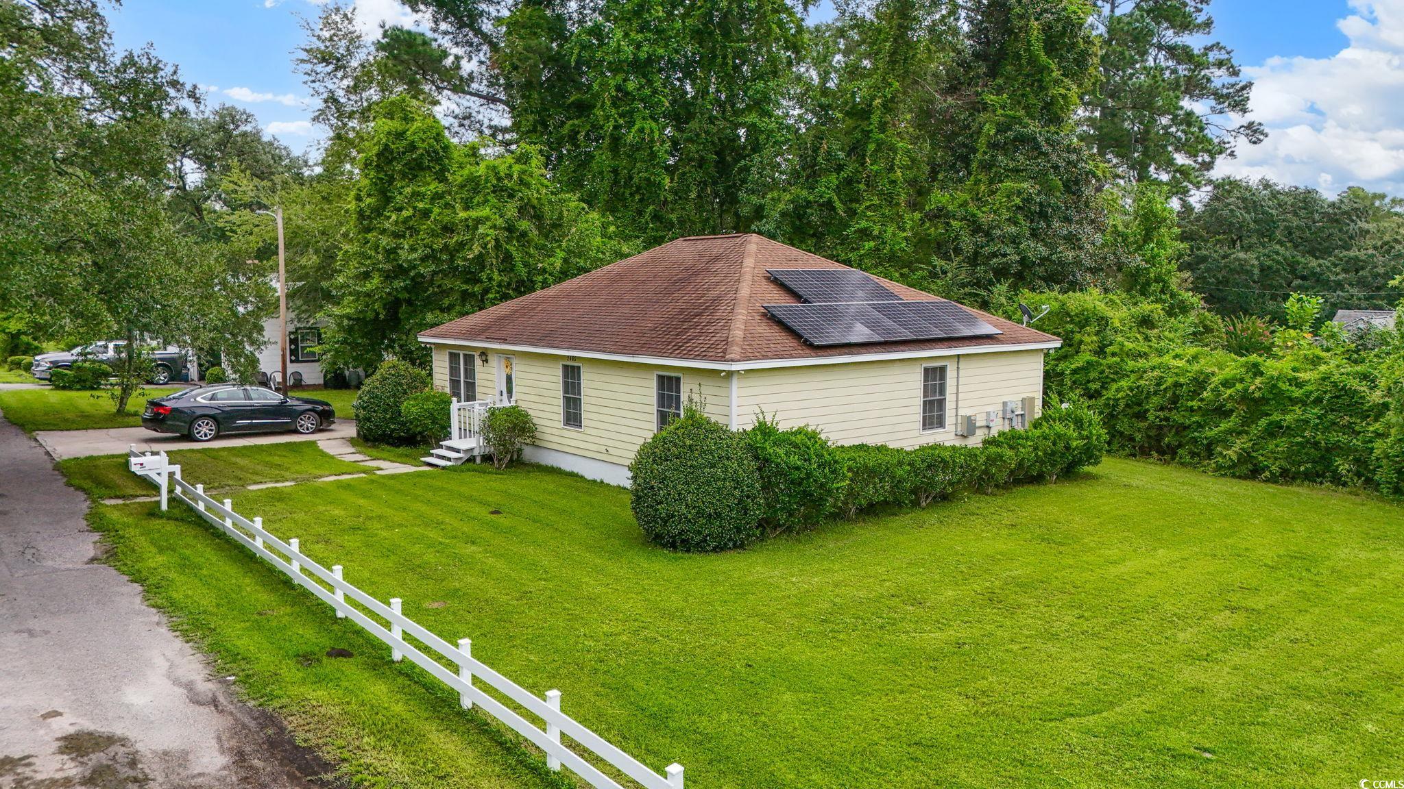 2405 Sherry Avenue Conway, SC 29527 - Photo 25 of 29 View of home's exterior featuring roof mounted solar panels, a yard, view of wooded area, and roof with shingles