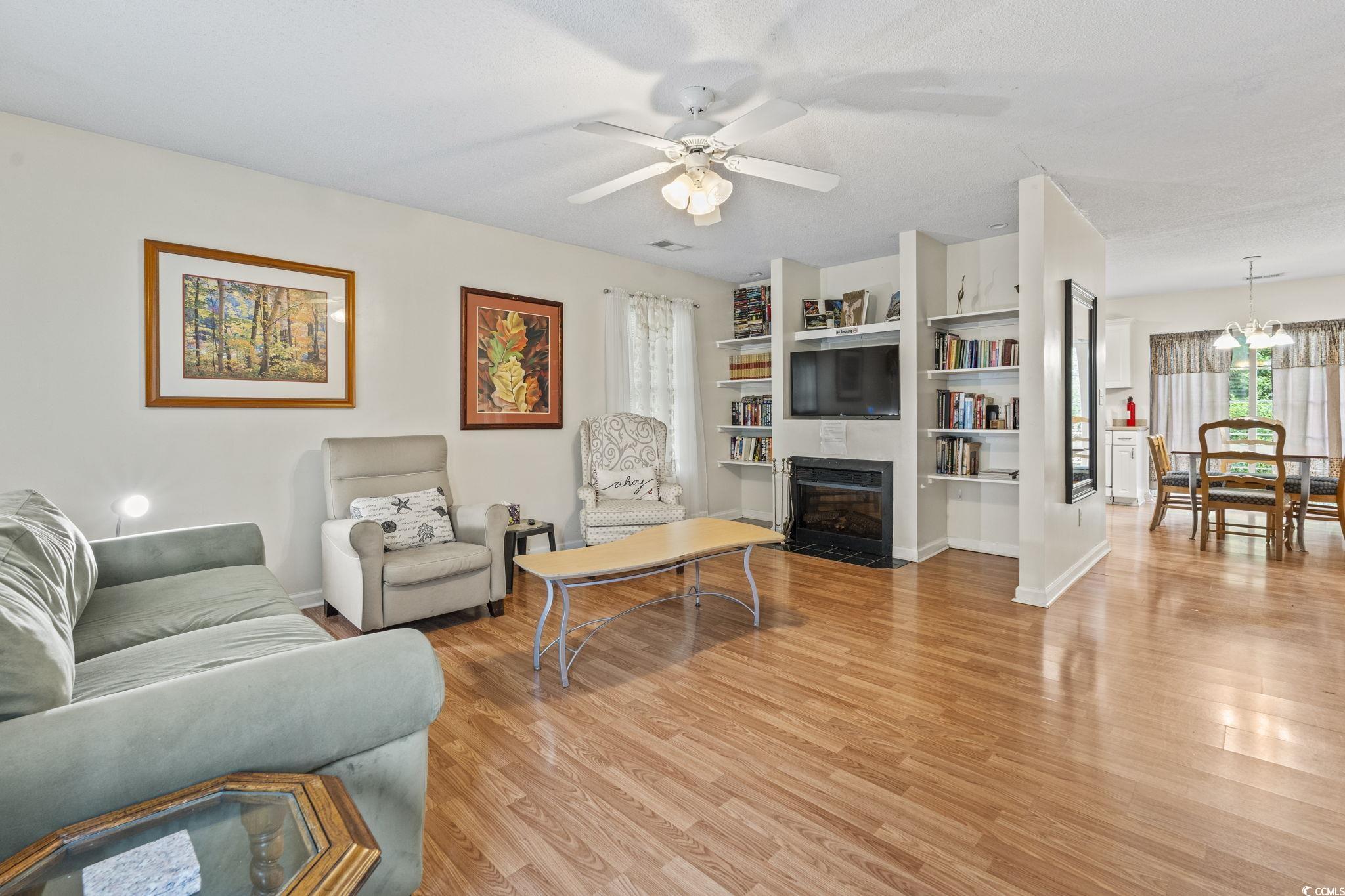 2405 Sherry Avenue Conway, SC 29527 - Photo 4 of 29 Living area with light wood-style flooring, a tiled fireplace, a ceiling fan, and a chandelier