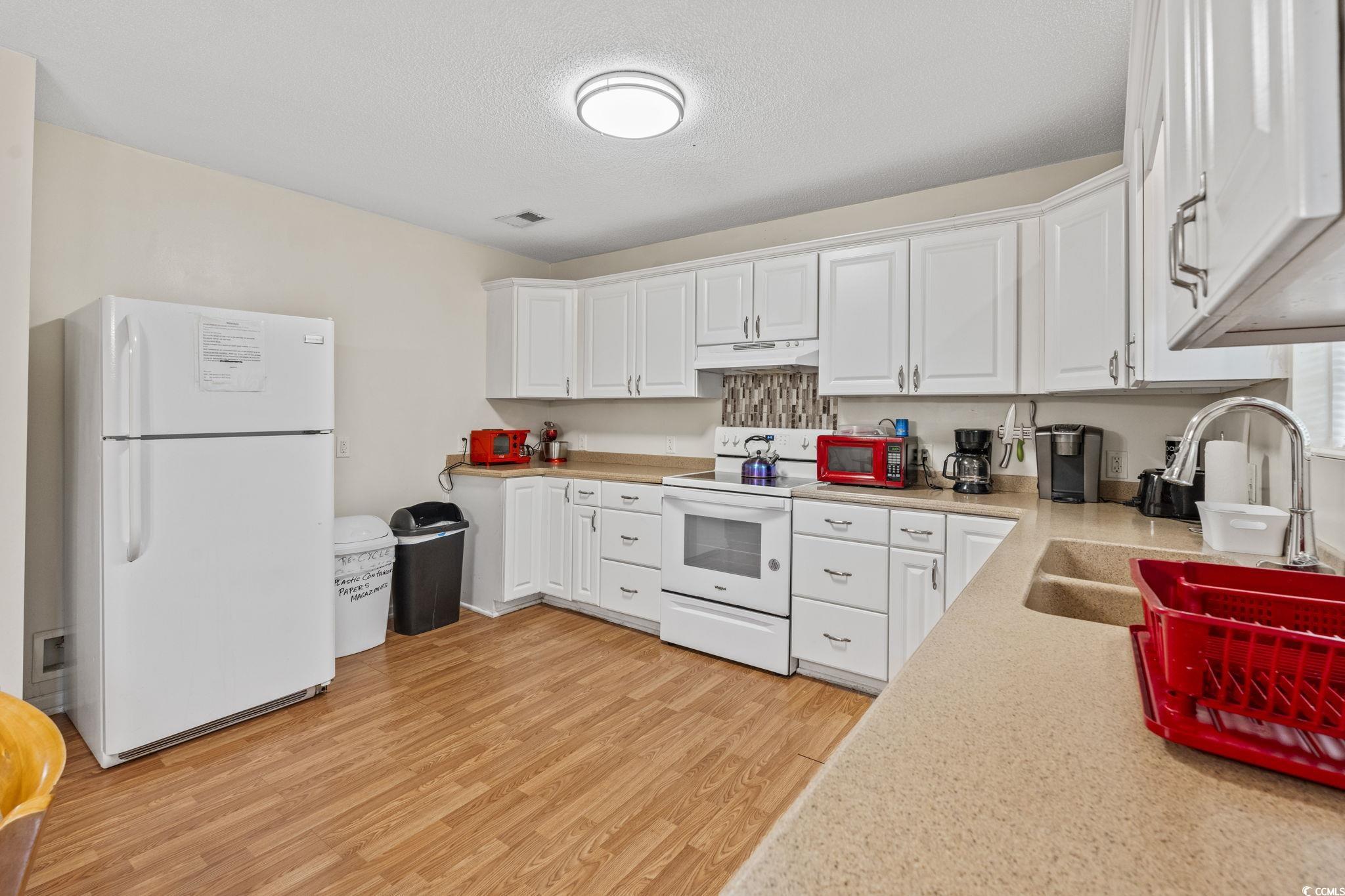 2405 Sherry Avenue Conway, SC 29527 - Photo 10 of 29 Kitchen featuring white appliances, light wood-style flooring, light countertops, white cabinets, and under cabinet range hood