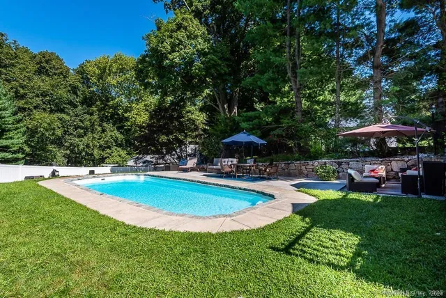 a view of a swimming pool with lawn chairs under an umbrella