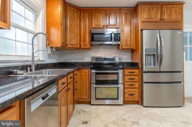 a kitchen with stainless steel appliances granite countertop a refrigerator stove and sink