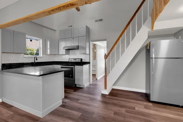 a kitchen with stainless steel appliances granite countertop a sink a stove a refrigerator and island with wooden floor