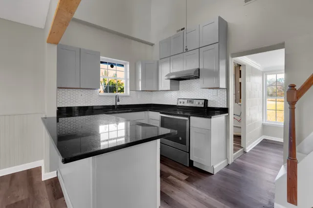 a kitchen with granite countertop white cabinets a sink a window and stainless steel appliances