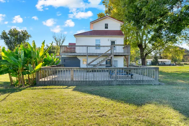 a view of a house with a yard and a large tree