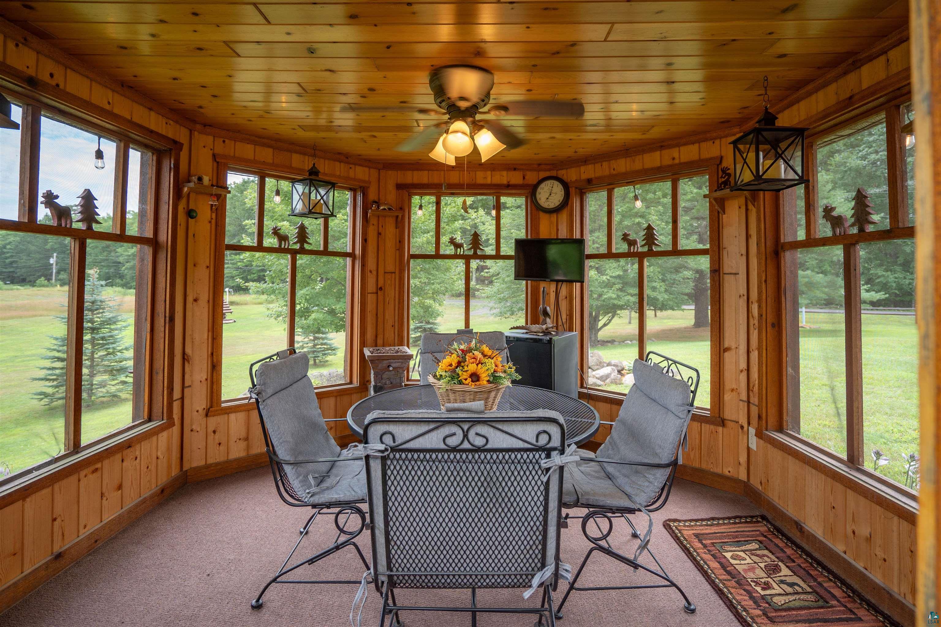 11911 East Rowe Road Lake Nebagamon, WI 54849 - Photo 31 of 61 Sunroom featuring extensive natural wood paneling, multiple large windows, a ceiling fan, and built-in lighting fixtures