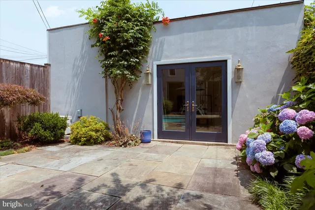 a front view of a house with lots of flowers and covered with trees