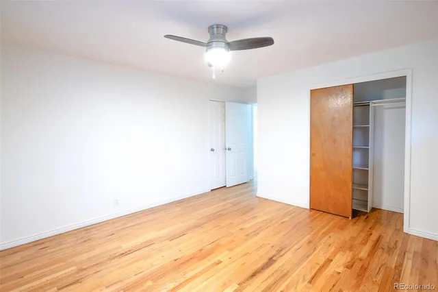 a view of empty room with wooden floor and ceiling fan
