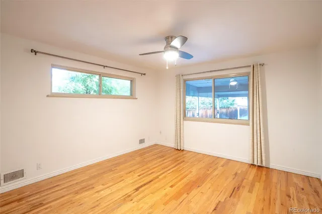 a view of empty room with wooden floor and fan