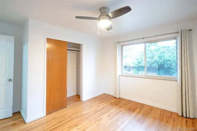 a view of empty room with wooden floor and fan