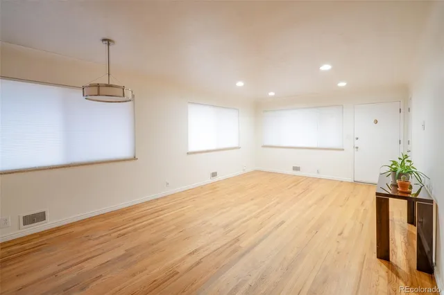 a room with a chandelier fan and wooden floor