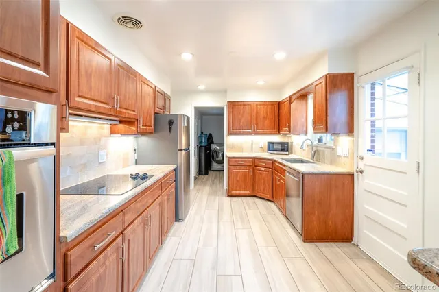 a kitchen with stainless steel appliances granite countertop a refrigerator a sink and a stove