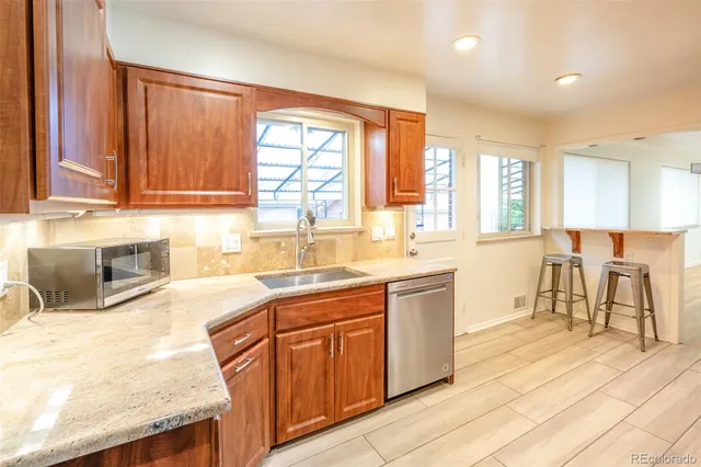 a kitchen with stainless steel appliances granite countertop wooden cabinets a sink and dishwasher a stove with wooden floors