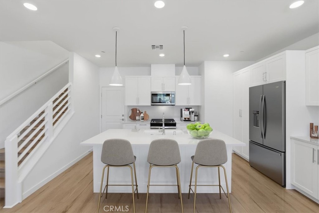 2378 Channel Drive, Unit 103 Ventura, CA 93003 - Photo 9 of 33 a kitchen with stainless steel appliances granite countertop a kitchen island a hardwood floor and chairs
