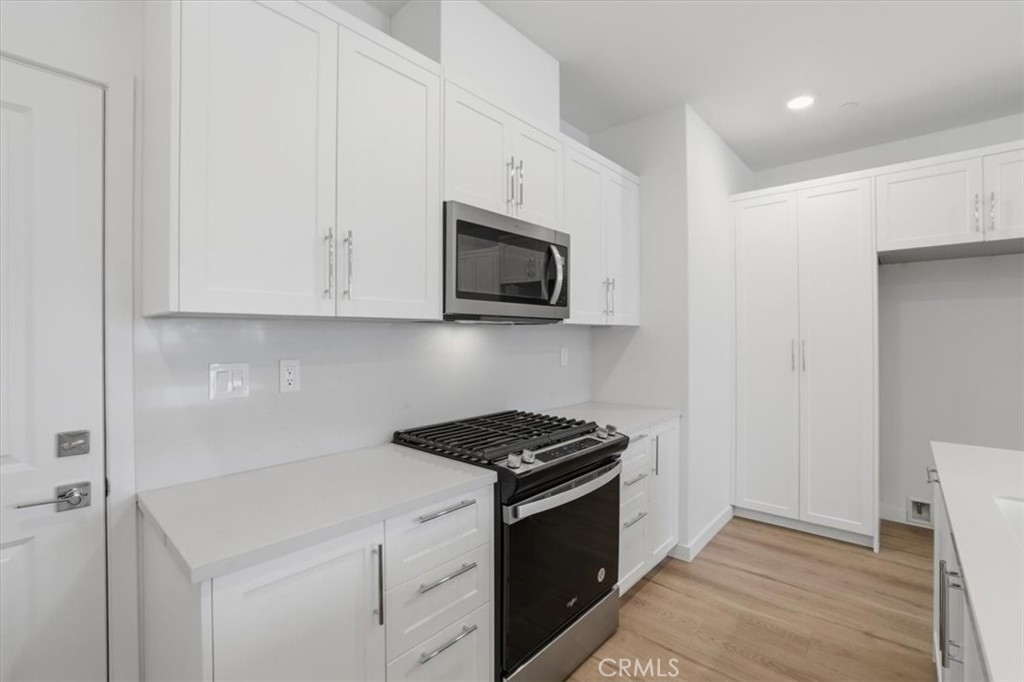 2378 Channel Drive, Unit 103 Ventura, CA 93003 - Photo 10 of 33 a kitchen with stainless steel appliances granite countertop white cabinets a stove top oven