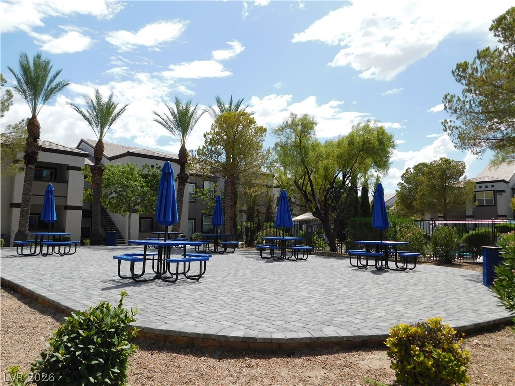 7255 West Sunset Road, Unit 2029 Las Vegas, NV 89113 - Photo 28 of 28 An inviting outdoor common area features multiple picnic tables with umbrellas, set on a paver patio amidst mature trees and landscaping.