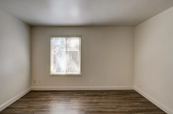 a view of an empty room with wooden floor and closet