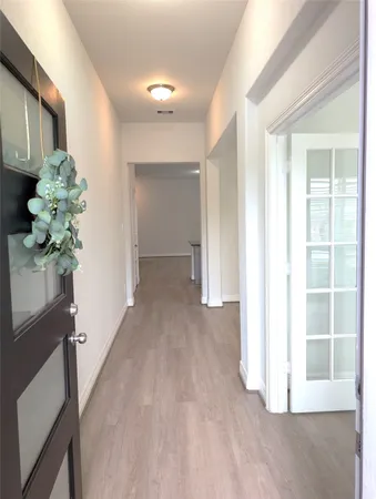 a view of hallway with window and wooden floor