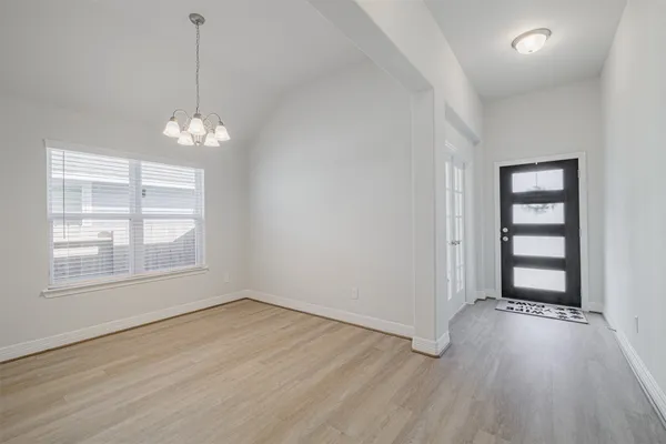 an empty room with wooden floor chandelier and windows