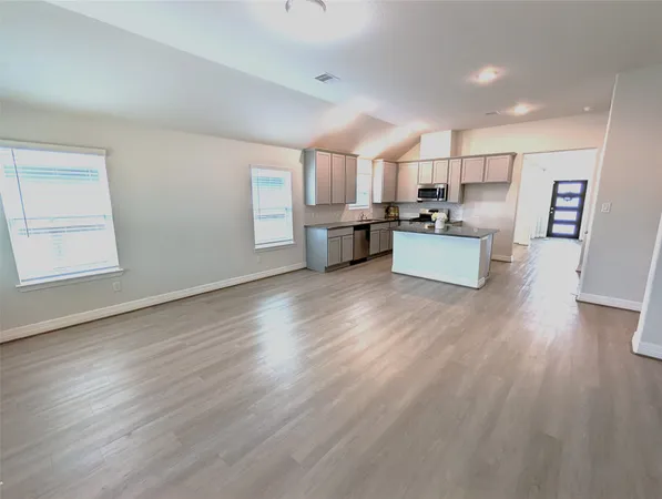 a kitchen with stainless steel appliances wooden floors and white walls