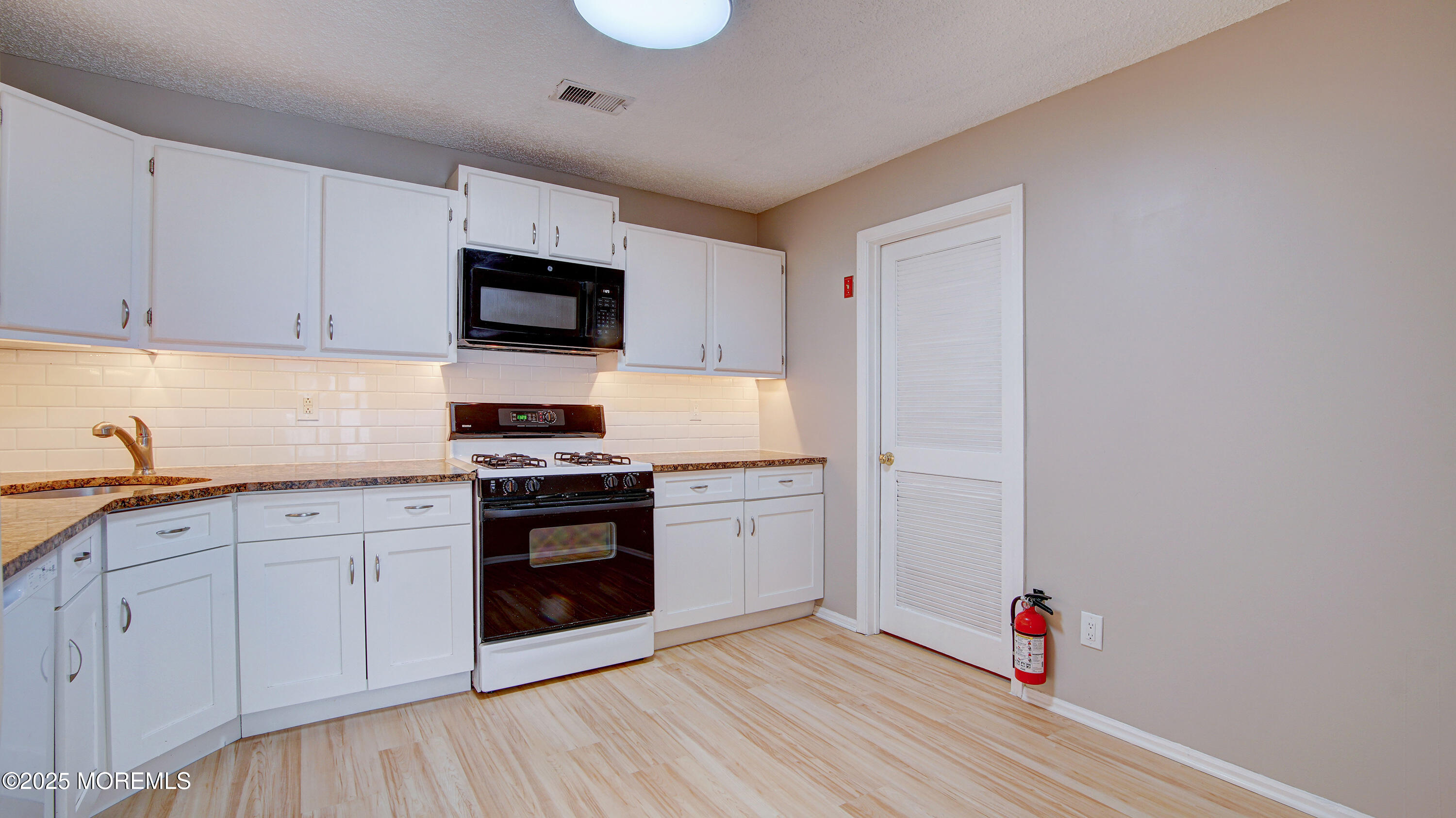 316 Tulip Lane Freehold, NJ 07728 - Photo 17 of 39 a kitchen with granite countertop white cabinets and stainless steel appliances