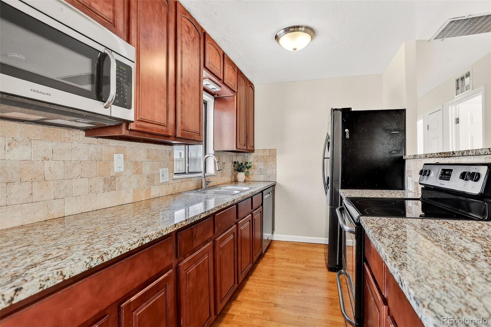 2836 South Grape Way Denver, CO 80222 - Photo 13 of 29 a kitchen with stainless steel appliances granite countertop a sink stove and refrigerator