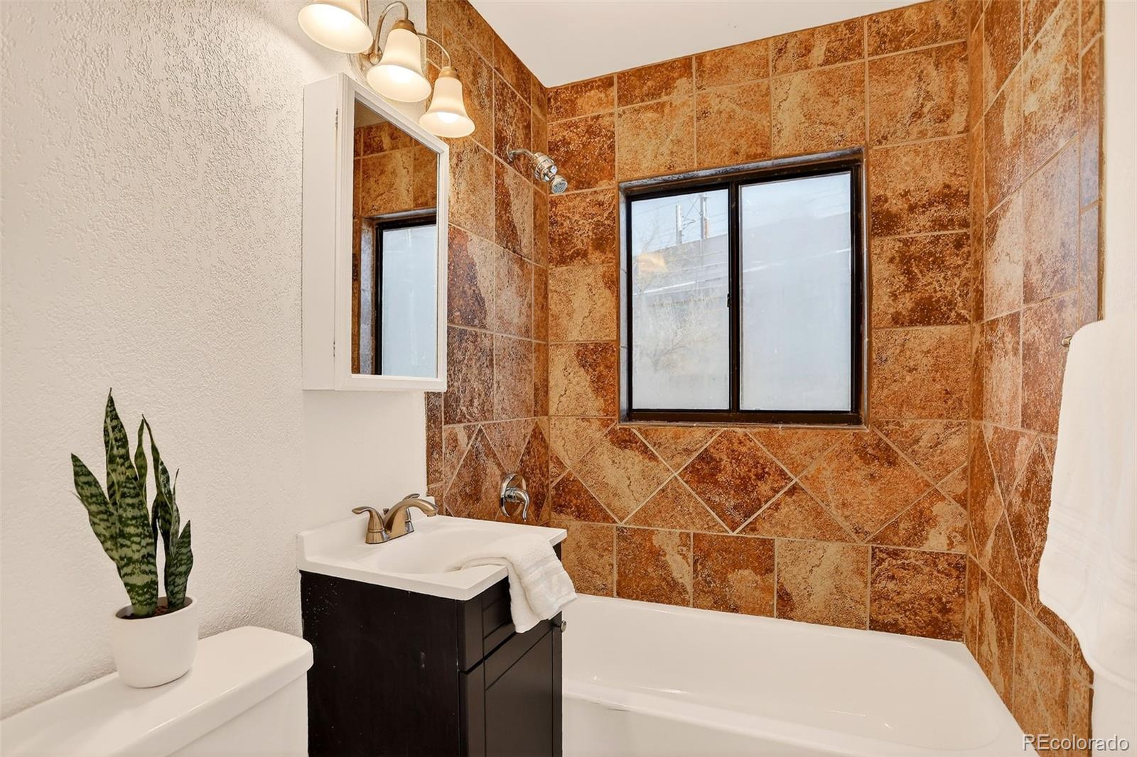 2836 South Grape Way Denver, CO 80222 - Photo 21 of 29 a bathroom with a sink a toilet and shower