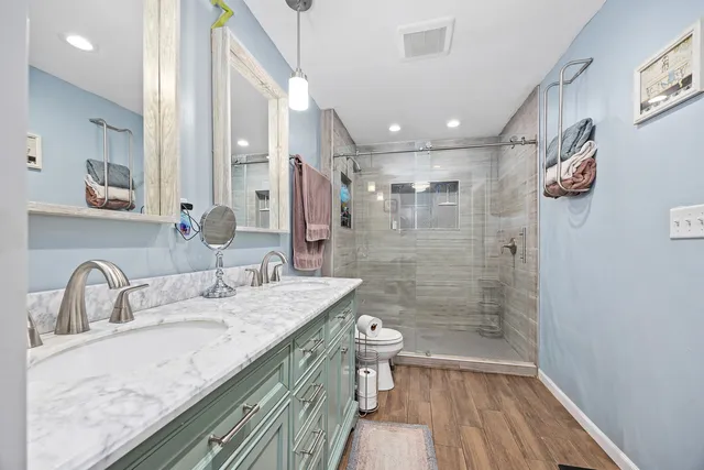 a bathroom with a granite countertop sink a toilet a mirror and shower