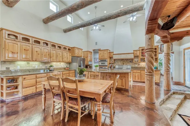 a kitchen with stainless steel appliances kitchen island granite countertop a table chairs sink and cabinets