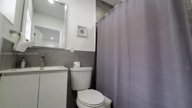 a bathroom with a sink a toilet a mirror and shower curtain