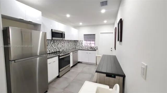 a kitchen with white cabinets and stainless steel appliances