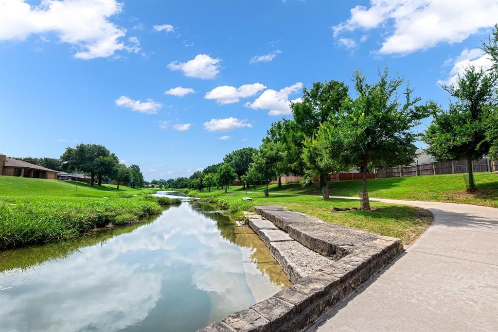 770 North Plano Road, Unit 303 Richardson, TX 75081 - Photo 24 of 26 Scenic view of a waterway bordered by lush green grass, mature trees, and a paved pathway