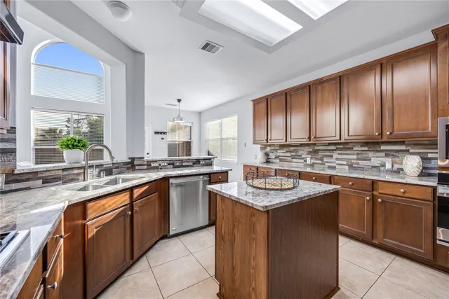 a kitchen with stainless steel appliances granite countertop a stove a sink and a microwave
