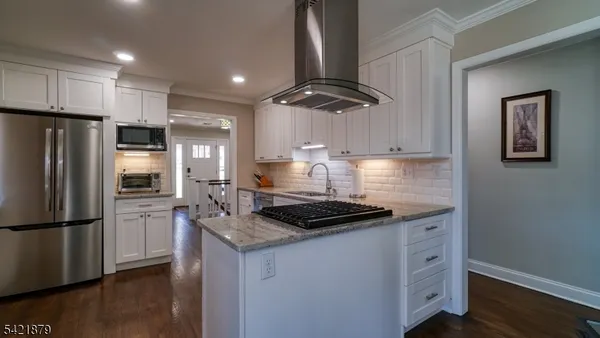 a kitchen with stainless steel appliances granite countertop a sink a stove a refrigerator and island
