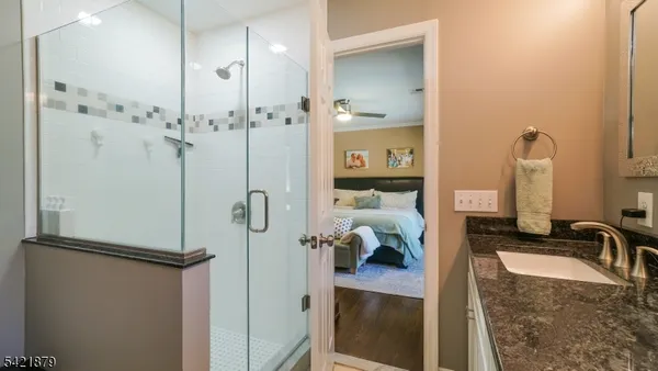 a bathroom with a granite countertop sink a mirror and shower