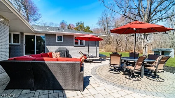 a view of a patio with table and chairs under an umbrella with a barbeque
