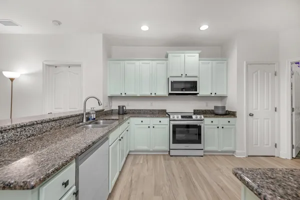 a kitchen with granite countertop a sink stove and cabinets