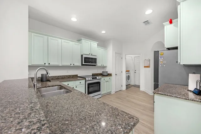 a kitchen with granite countertop a sink stove and refrigerator