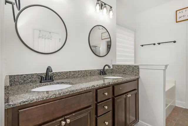 a bathroom with a granite countertop double vanity sink and a mirror