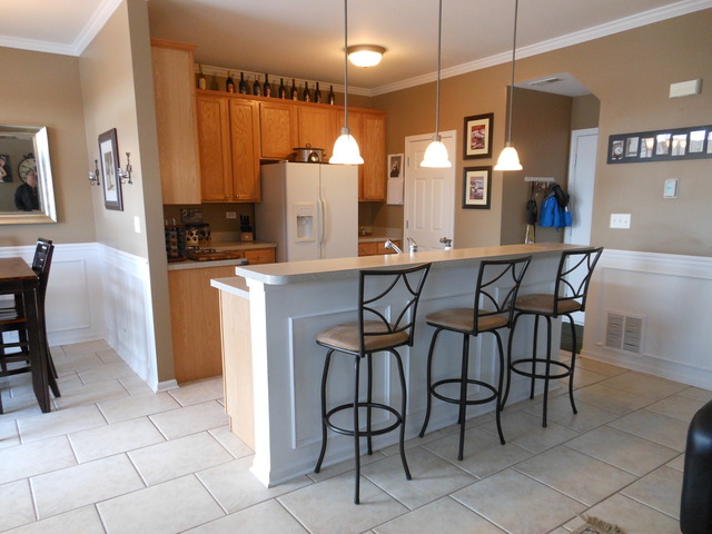 549 Springbrook Trail North Oswego, IL 60543 - Photo 6 of 19 a dining room with stainless steel appliances kitchen island granite countertop a table chairs and a refrigerator