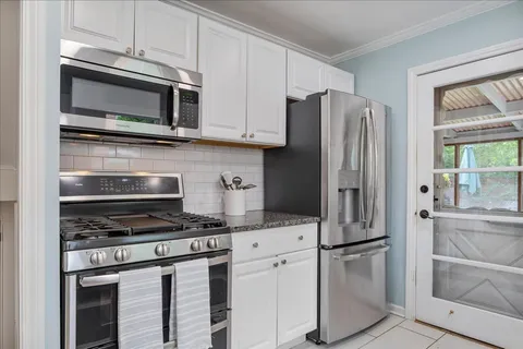 a kitchen with stainless steel appliances white cabinets and a stove a refrigerator with wooden floor