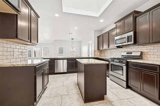 a kitchen with stainless steel appliances granite countertop a stove a sink and a microwave