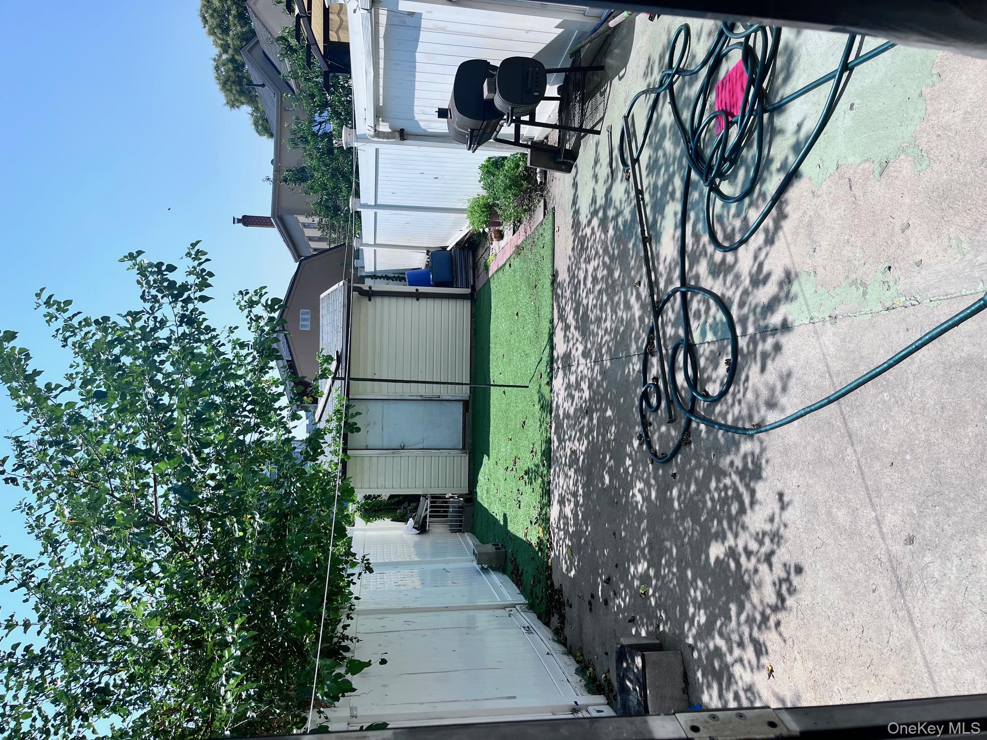 95-20 89th Street Queens, NY 11416 - Photo 2 of 5 a backyard of a house with barbeque oven and a table and chairs