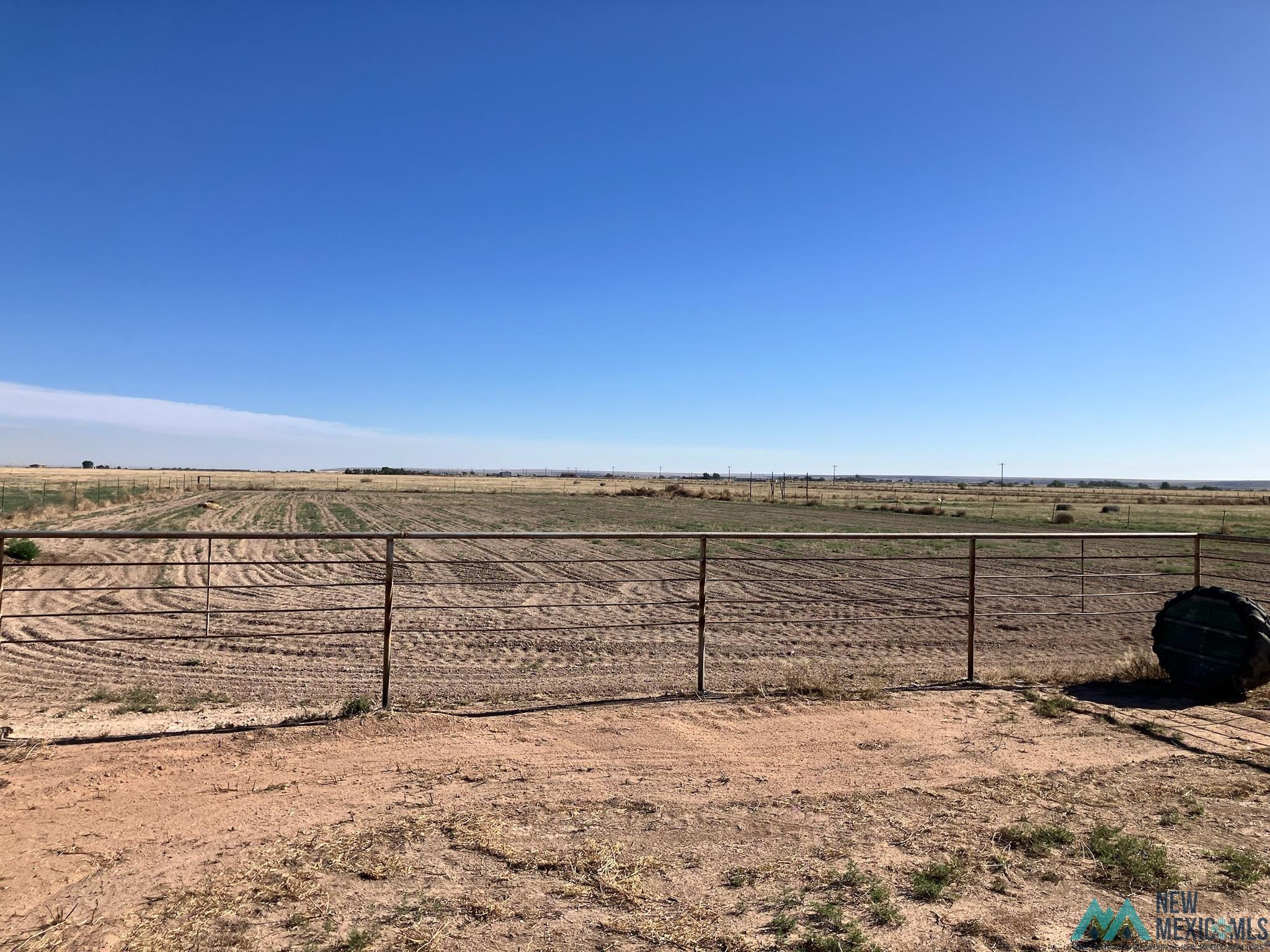 6660 Cherokee Road Dexter, NM 88230 - Photo 41 of 46 Expansive rural acreage featuring a metal fence, open fields, and distant vegetation under a clear sky