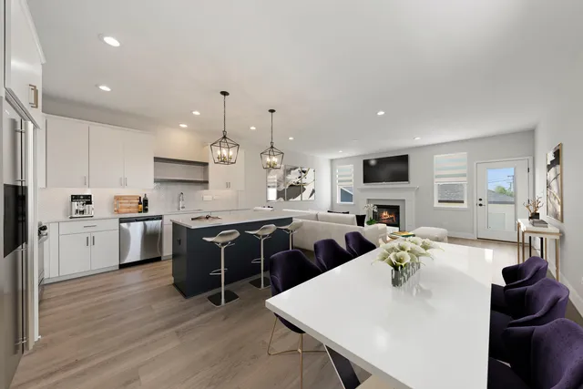 a open dining room with stainless steel appliances kitchen island granite countertop a stove top oven a sink dishwasher a dining table and chairs with wooden floor