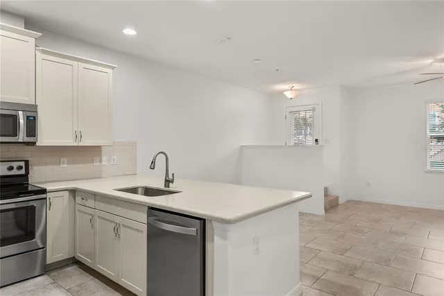 a kitchen that has a sink a stove and white cabinets with wooden floor