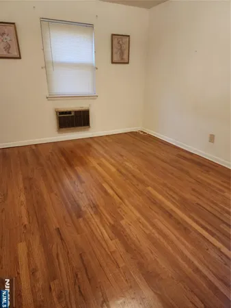 a view of empty room with wooden floor and kitchen view